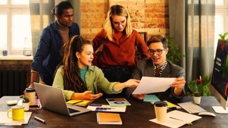 A group of people looking at an article to symbolize how to stand out on social media as a real estate agent.