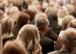 A photograph of a crowd of people from the back; a sea of heads.