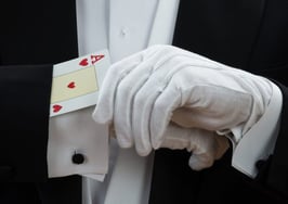 A magician hiding a card up the sleeve of his tuxedo