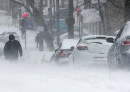 A blizzard with blocked cars, red lights and people walking in the snow