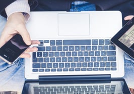 A man on his laptop with a cell phone and tablet.
