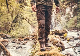 A man walking on a log over a stream