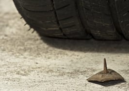 A tire about to drive over a rusty nail