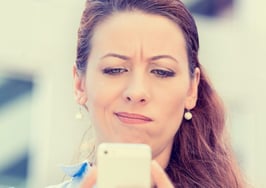A woman looking skeptically at her phone.