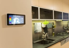 A smart home panel on a wall near a kitchen