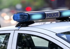 A police car with a policeman standing in front of it.