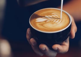 A barista pouring latte art into a latte