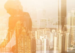 A woman on a computer reflected in a city-view window