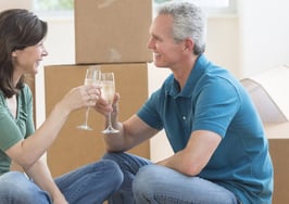 A couple sharing a champagne toast on the floor in their new house