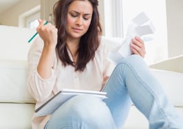 A woman sitting on her living-room floor going over bills.