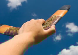 A hand holding a boomerang, preparing to throw