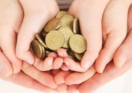 A family holding coins in the palms of their layered hands