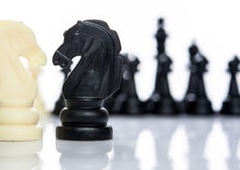 A black knight and white knight facing off on a marble table