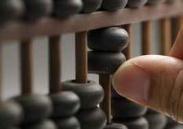 A hand moving beads on an abacus