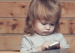 A little girl on a phone and computer