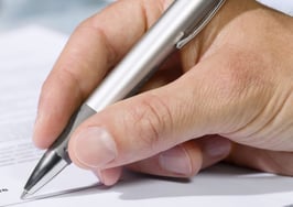 A hand signing a document