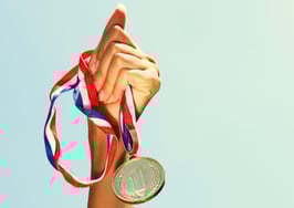 A woman holding a gold medal aloft