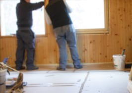 Two men installing a window in a house