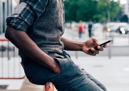 A millennial black man using a cell phone