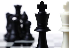 Black and white chess pieces facing each other across a board