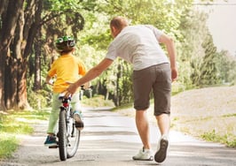 A father helping his son ride a bicycle