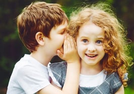 A young boy telling a young girl a secret