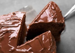 A piece of chocolate cake being removed from the whole
