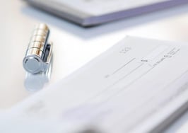 A man's hand writing a check