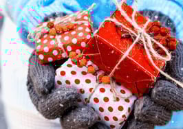 Gloved hands holding out holiday-wrapped gifts