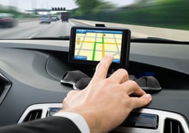 A man's hand navigating GPS while driving