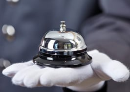 A white-gloved hand holding a concierge bell