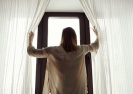 A woman opening the curtains