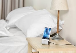 A smartphone by the side of a bed