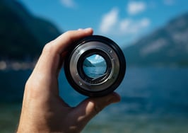 photo of man's hand holding up camera lens