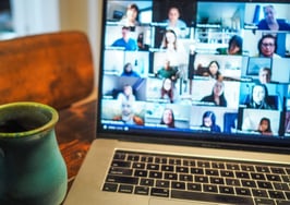 cup of coffee next to laptop with online meeting in progress