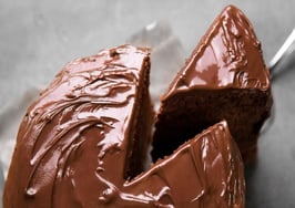 A piece of chocolate cake being removed from the whole