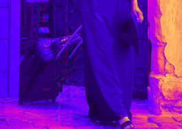 An image of a person exiting through a door with a rolling suitcase to symbolize a brokerage exit checklist.