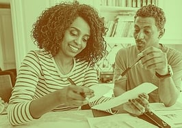 A couple sitting at the table, looking at taxes to represent a homeowner tax tip.