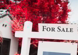 A for-sale sign posted in front of a residential home