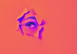 Woman's eye showing through tear in paper to symbolize Opendoor's CEO resignation.