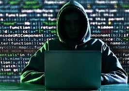 Man in hooded sweatshirt with no face in front of computer code to represent pig butchering financial scam