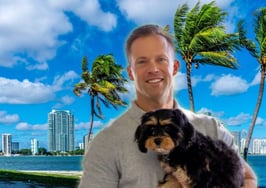 A photo of Darin Tansey with his dog in front of a beach in Miami