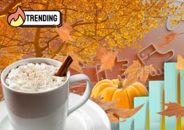 Flat lay of cozy autumn items, including a pumpkin, PSL coffee cup, tree with changing leaves, and leaves swirling — evoking fall marketing trends and seasonal storytelling.