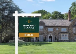 A for-sale yard sign with Howard Hanna's new logo in front of a residential home