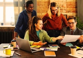 A group of people looking at an article to symbolize how to stand out on social media as a real estate agent.