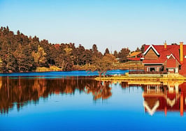 A beautiful home on a lake during autumn to illustrate fall listing refresh strategies.