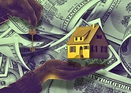 An image of hands holding a house and keys over a background of money to signify questionable real estate industry standards.