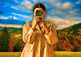 An image of a woman standing in front of an autumnal background to represent fall video content ideas.