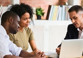 Real estate agent discusses Zillow Preview RealScout listings with buyers on a laptop