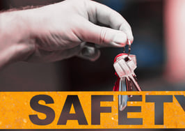 An image of keys in a hand over safety tape to signify real estate safety resources.